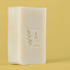 Savon blanc avec logo sur fond jaune.