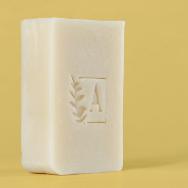 Savon blanc avec logo sur fond jaune.