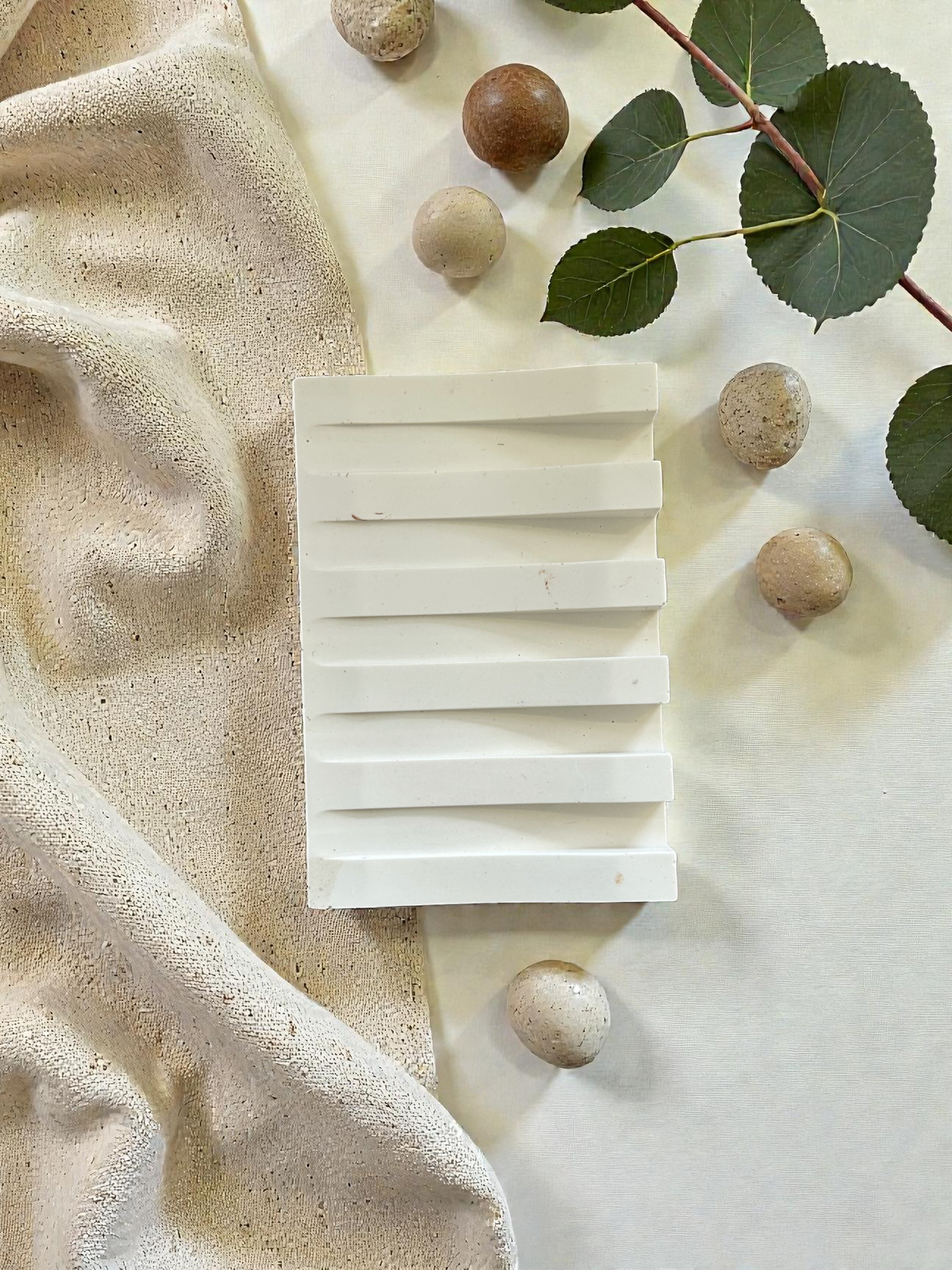 Objet blanc texturé sur tissu et éléments naturels.