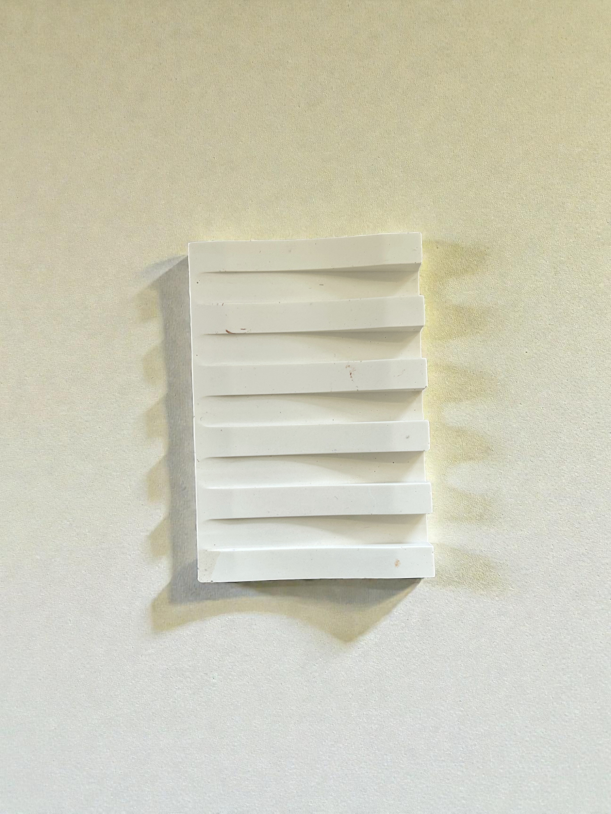 Élément décoratif en relief blanc sur fond neutre.